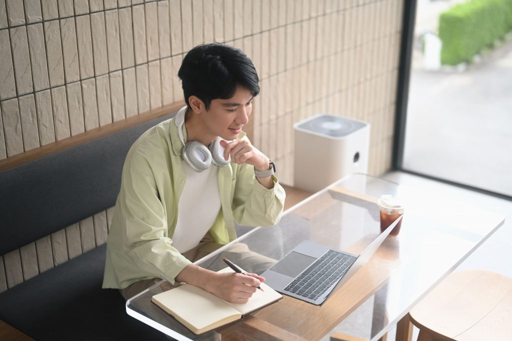 ชายหนุ่มกำลังนั่งอ่านข้อมูลจากอินเทอร์เน็ตว่า Ambivert คือคนประเภทใด